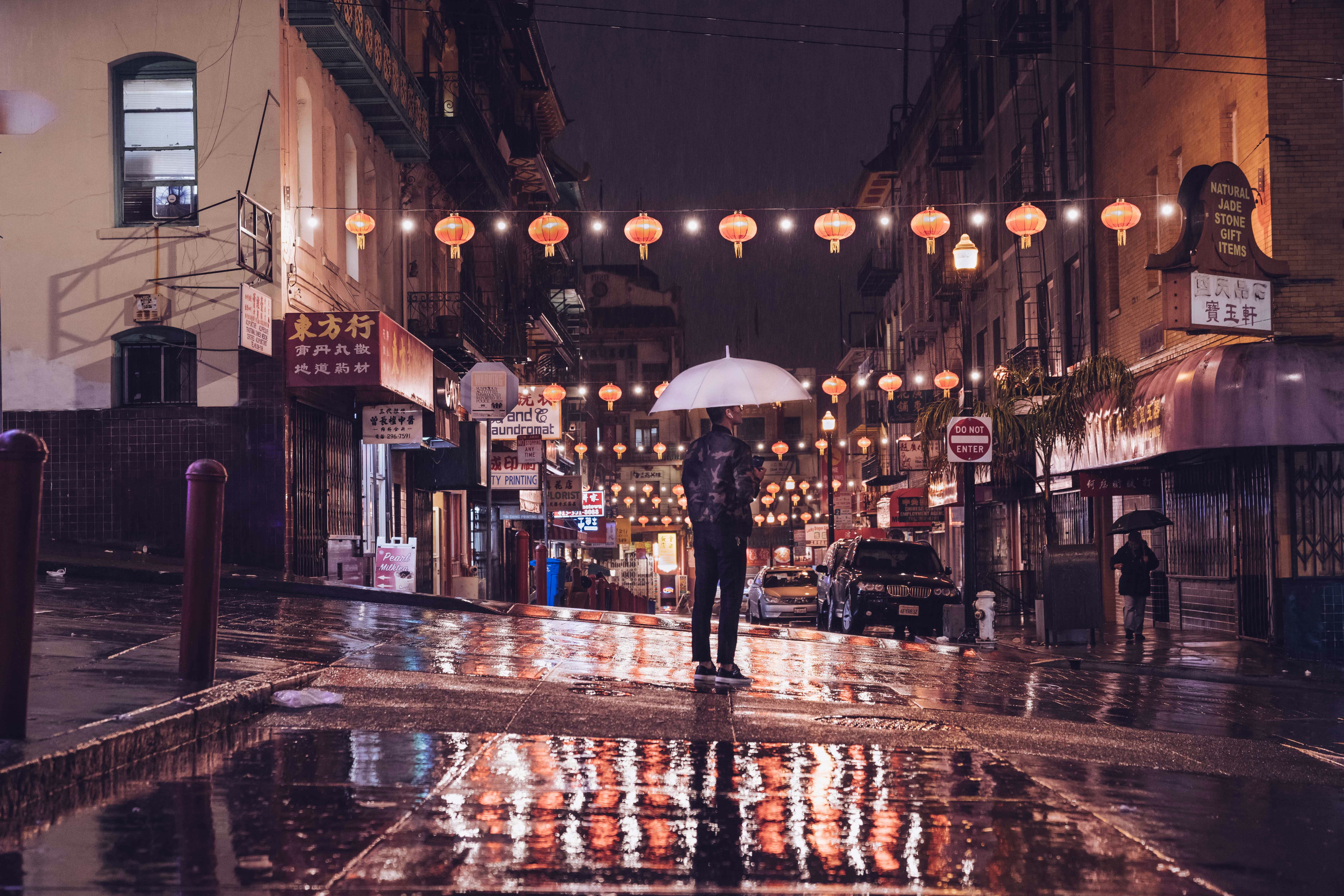 person standing on street holding umbrella during night time